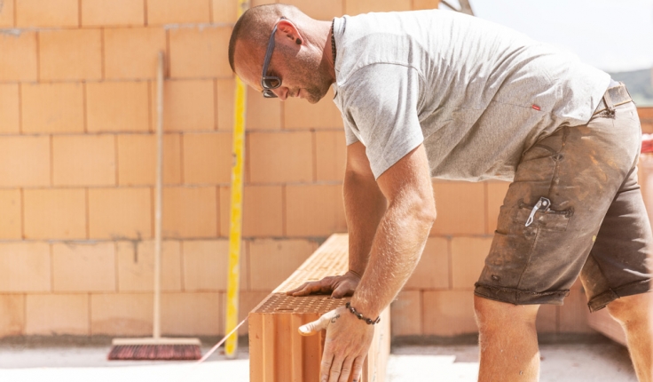 Mitarbeiter setzt Steine am Lotband beim Mauern