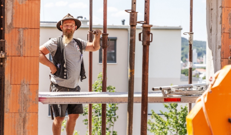 Mitarbeiter an Stützen schaut durch Hauseingang im Rohbau